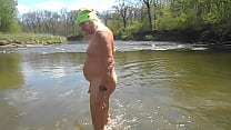 裸の運転手が川に立ち、振り払う