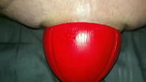Enorme bola de futebol vermelha com 12 cm de largura deslizando para fora da minha bunda de perto em câmera lenta