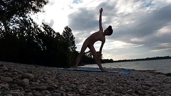 Un chico nudista delgado hace yoga desnudo en una playa naturista. Vídeo de yoga desnudo del modelo porno gay Jon Arteen